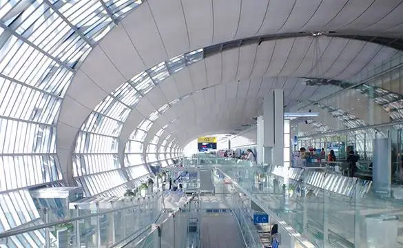 Modern government or public building interior with glass walls, bright lighting, and people walking through the corridor.