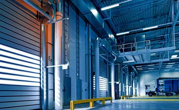 Clean and well-lit industrial warehouse with a delivery truck parked near loading bays.