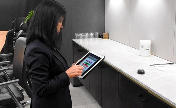 Female professional using a tablet to monitor cleaning tasks in an office reception area.